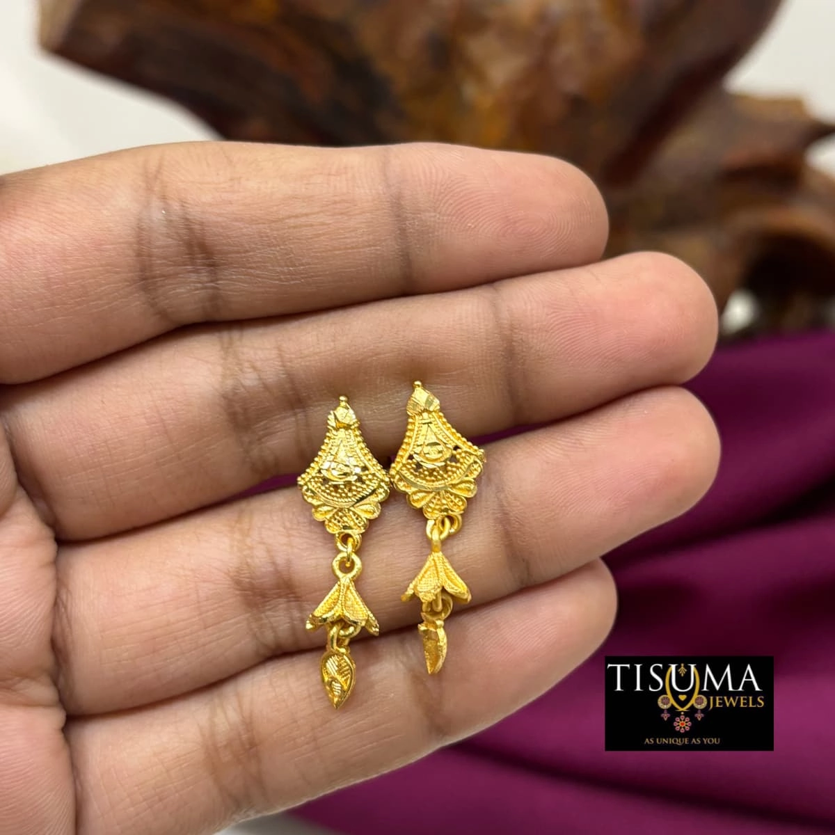 Traditional gold-tone drop earrings with triangular detailing and hanging leaf charms