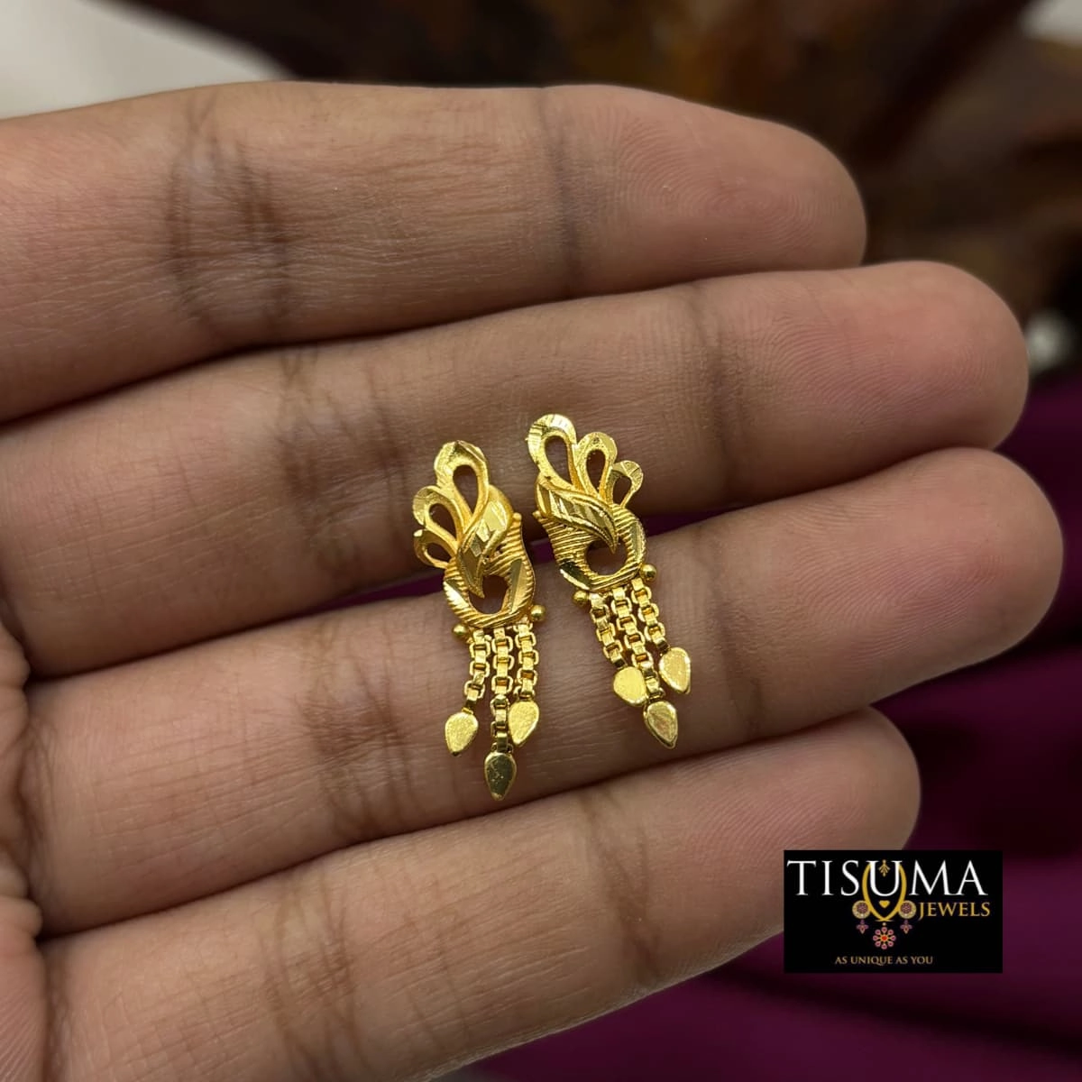 Gold-tone peacock-inspired earrings with hanging chains and leaf charms