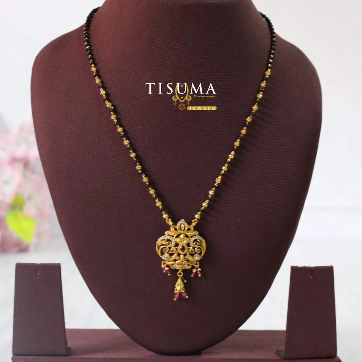 Traditional gold-finish black beads mangal sutra with an ornamental pendant and pink and green accents