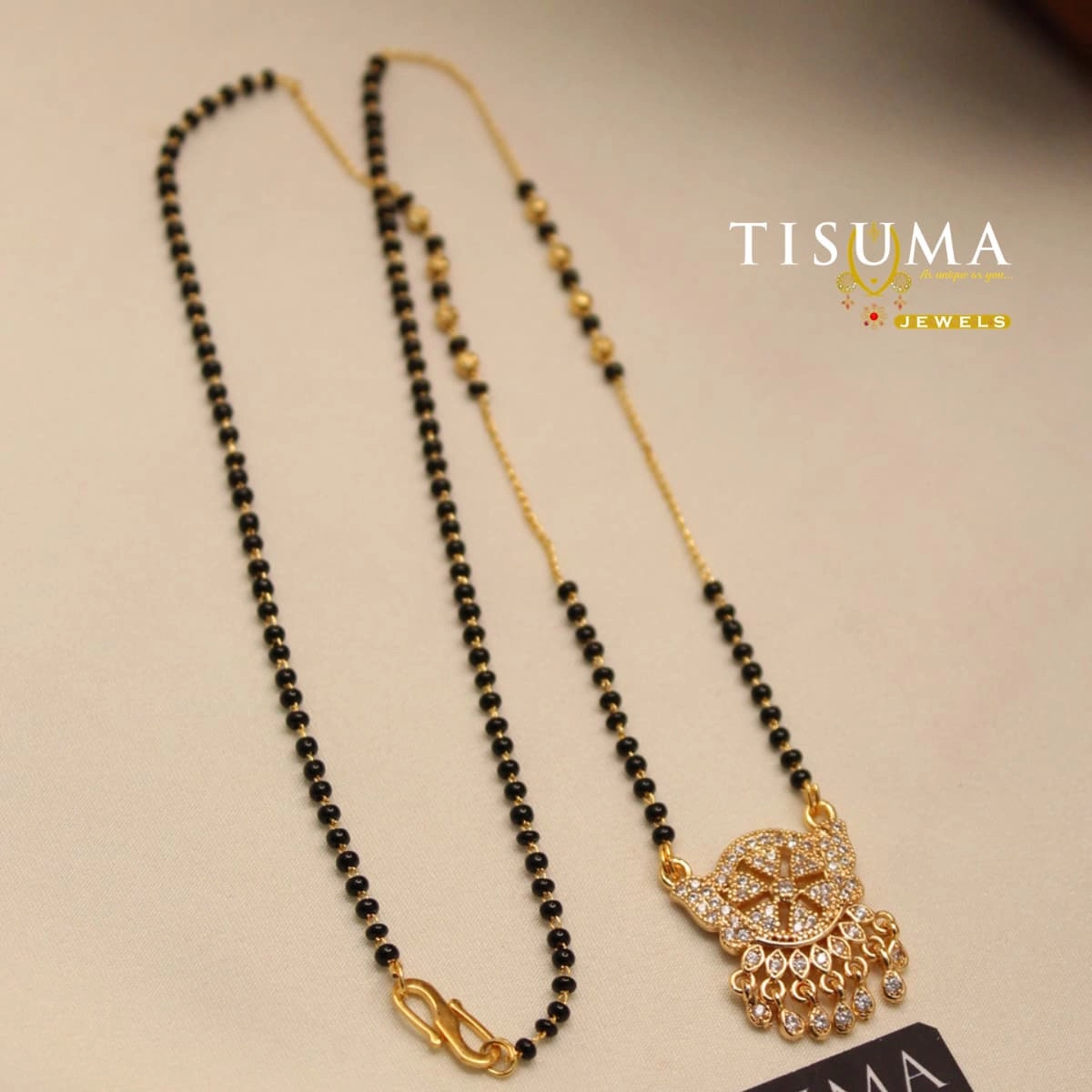 Black beads mangal sutra with gold-tone floral pendant and white AD stones