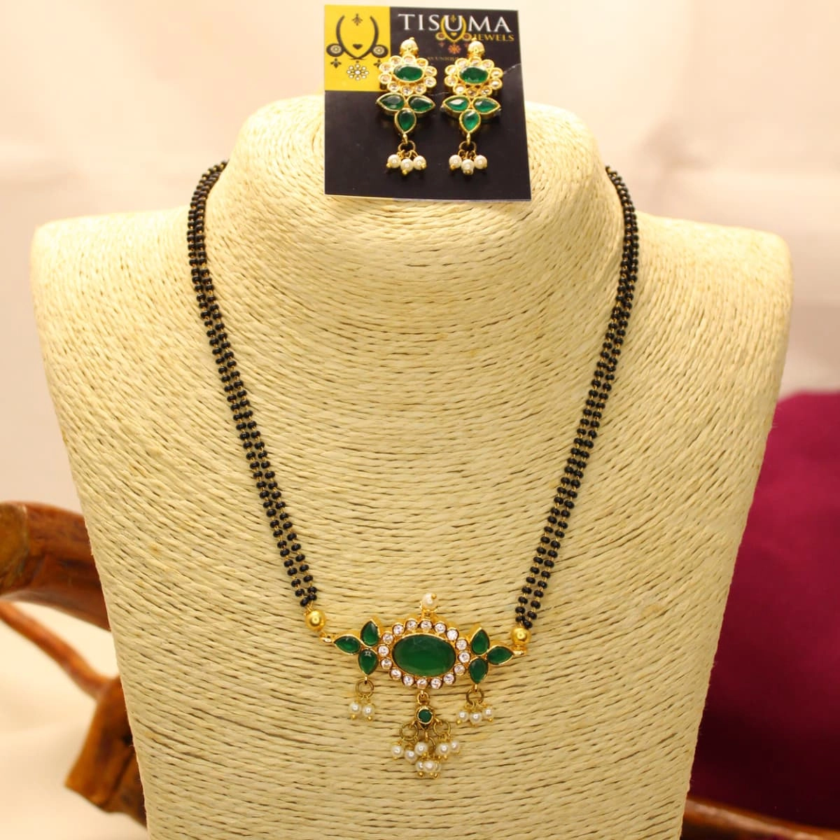 Double-line black beads mangal sutra with green oval pendant, white stone accents and pearl drops