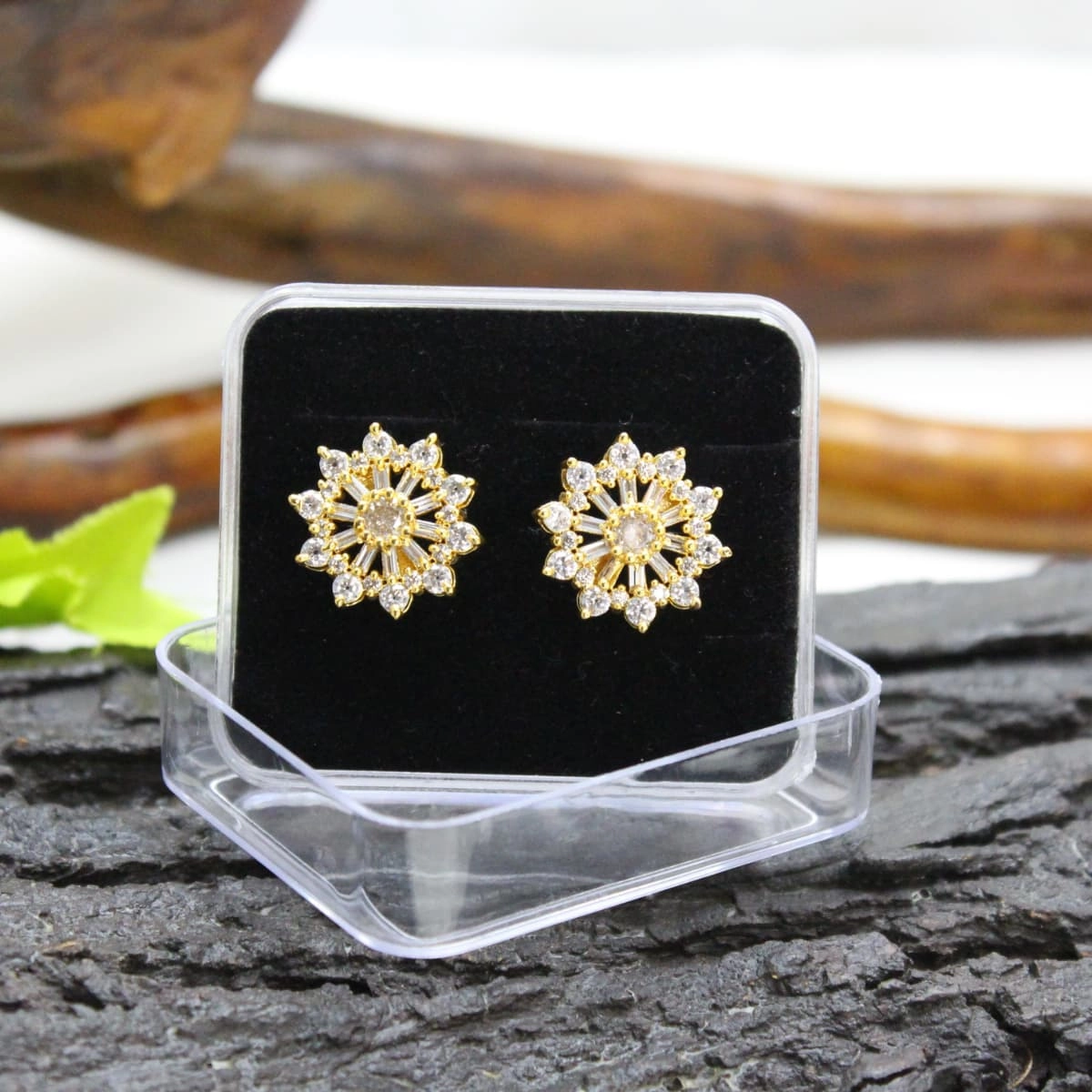 Gold tone sunburst stud earrings with a central clear stone and sparkling baguette-style and round stone accents