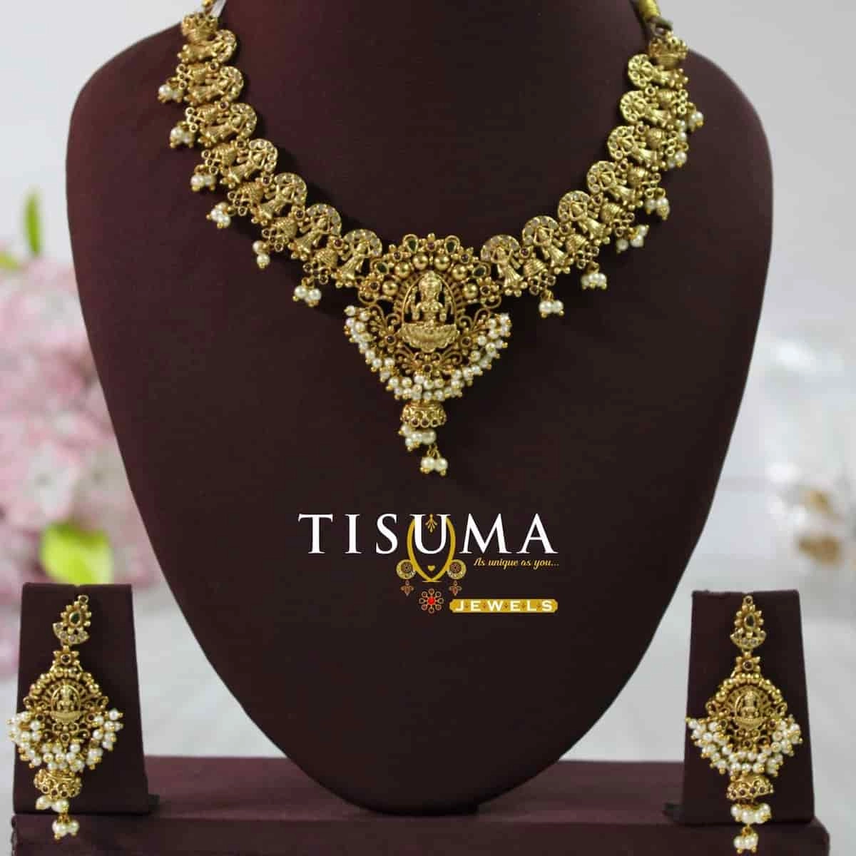 Antique gold finish matte necklace featuring a Goddess Lakshmi pendant, traditional peacock motifs, pearl drop detailing, and matching statement earrings | Tisuma Jewels