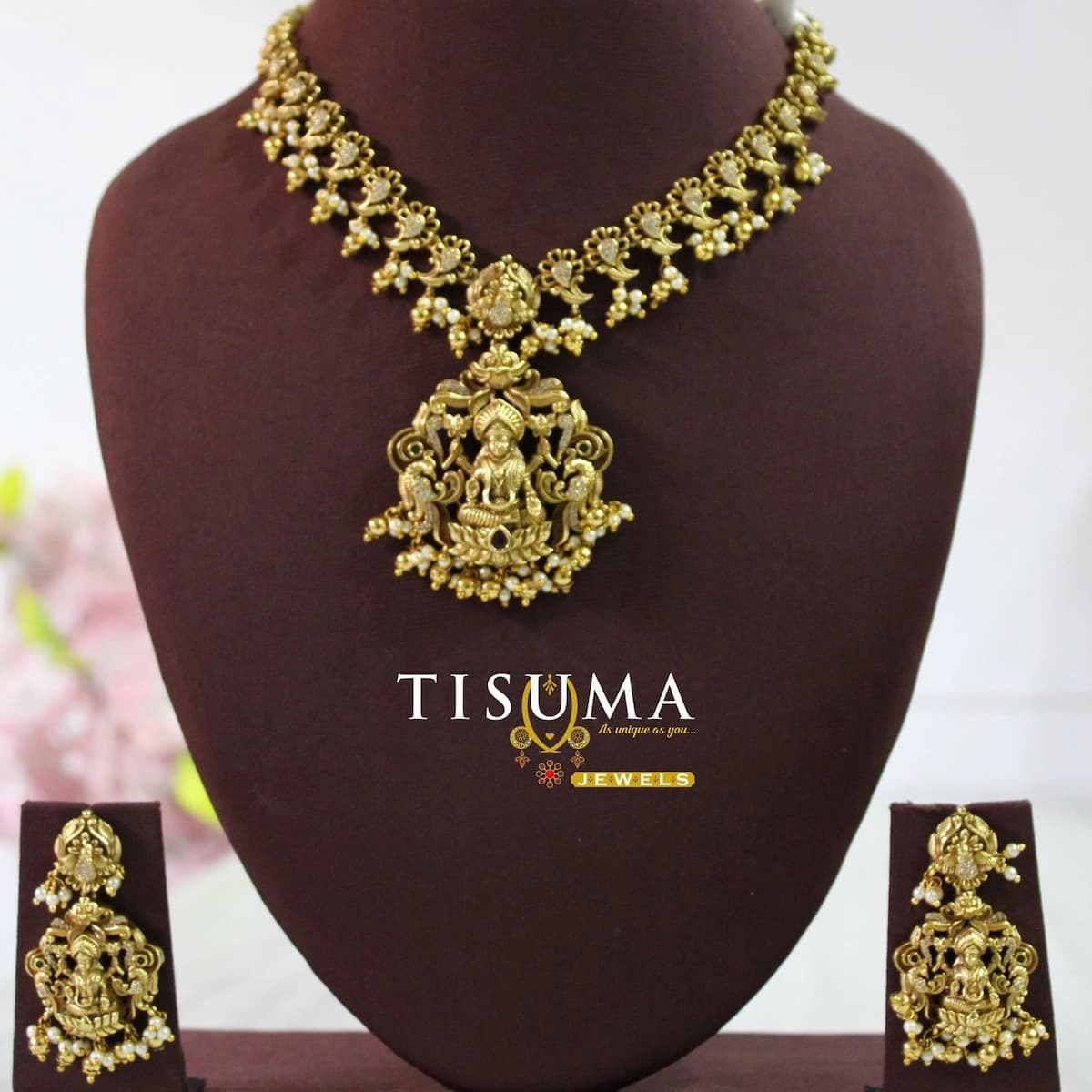 Antique gold Lakshmi temple necklace set with intricate goddess pendant, traditional floral detailing, pearl drops and matching earrings by Tisuma Jewels.