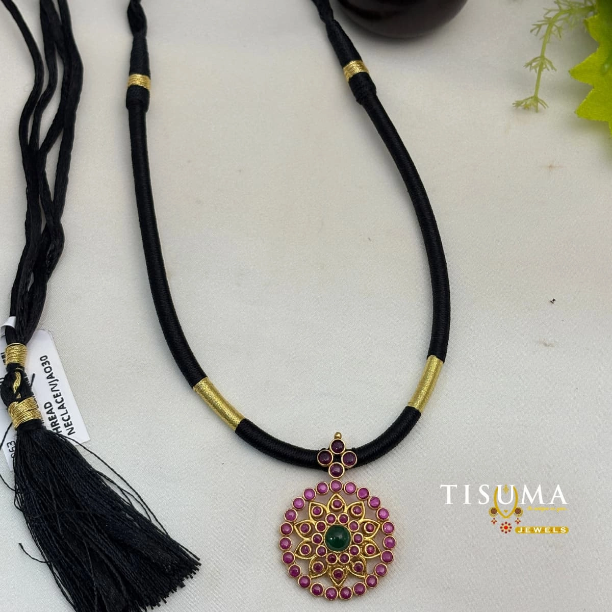 Black thread necklace with antique gold finish pendant, pink and green stone floral design, and gold accents by Tisuma Jewels.