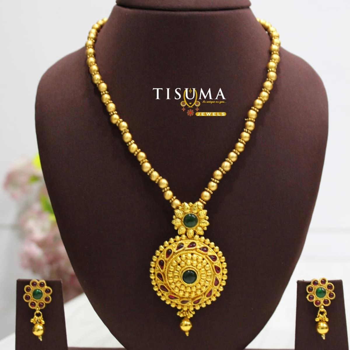 Traditional gold-finish round pendant necklace set with green and ruby colour stones and matching earrings