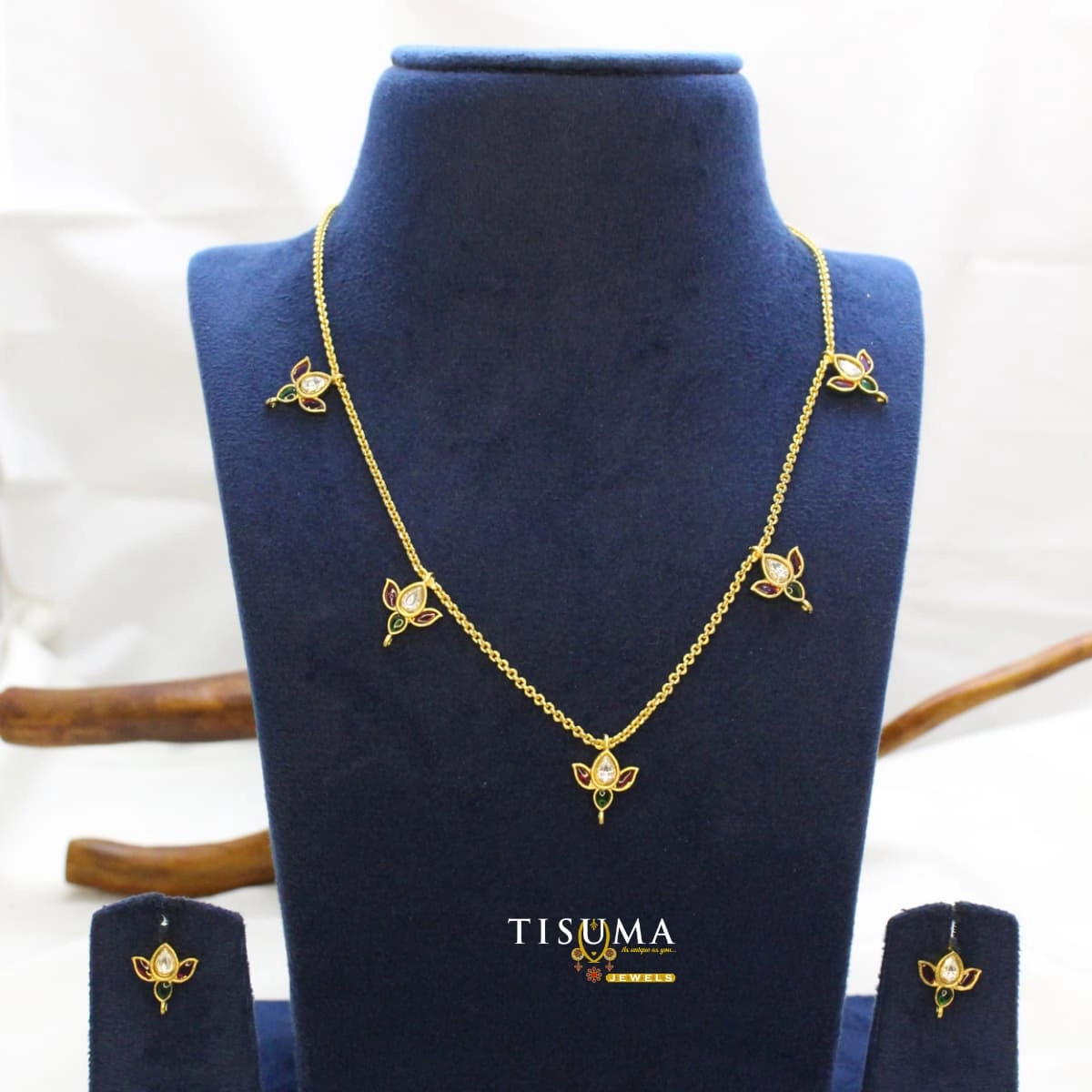 Gold-finish floral necklace set with ruby, green and white stones, delicate chain design and matching earrings | Tisuma Jewels