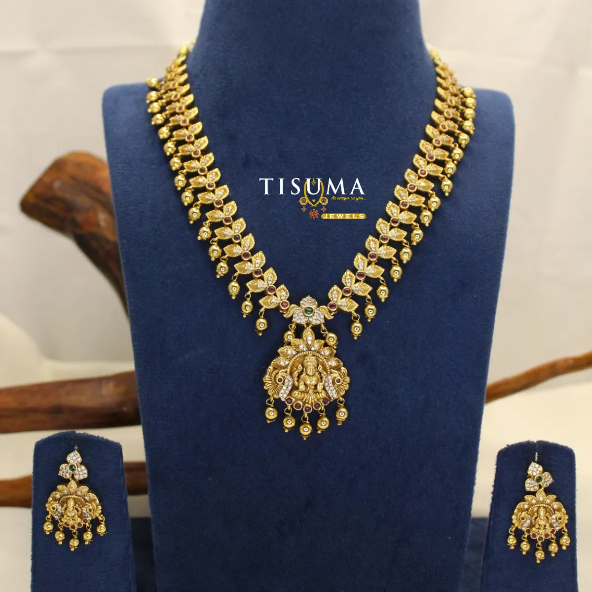 Antique gold-finish Lakshmi pendant necklace set with leaf motifs, stone detailing and matching earrings