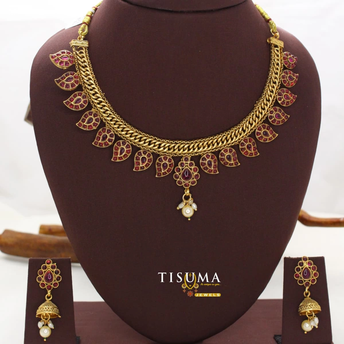 Gold finish necklace with ruby red stone motifs and matching jhumka earrings with pearl drops by Tisuma Jewels