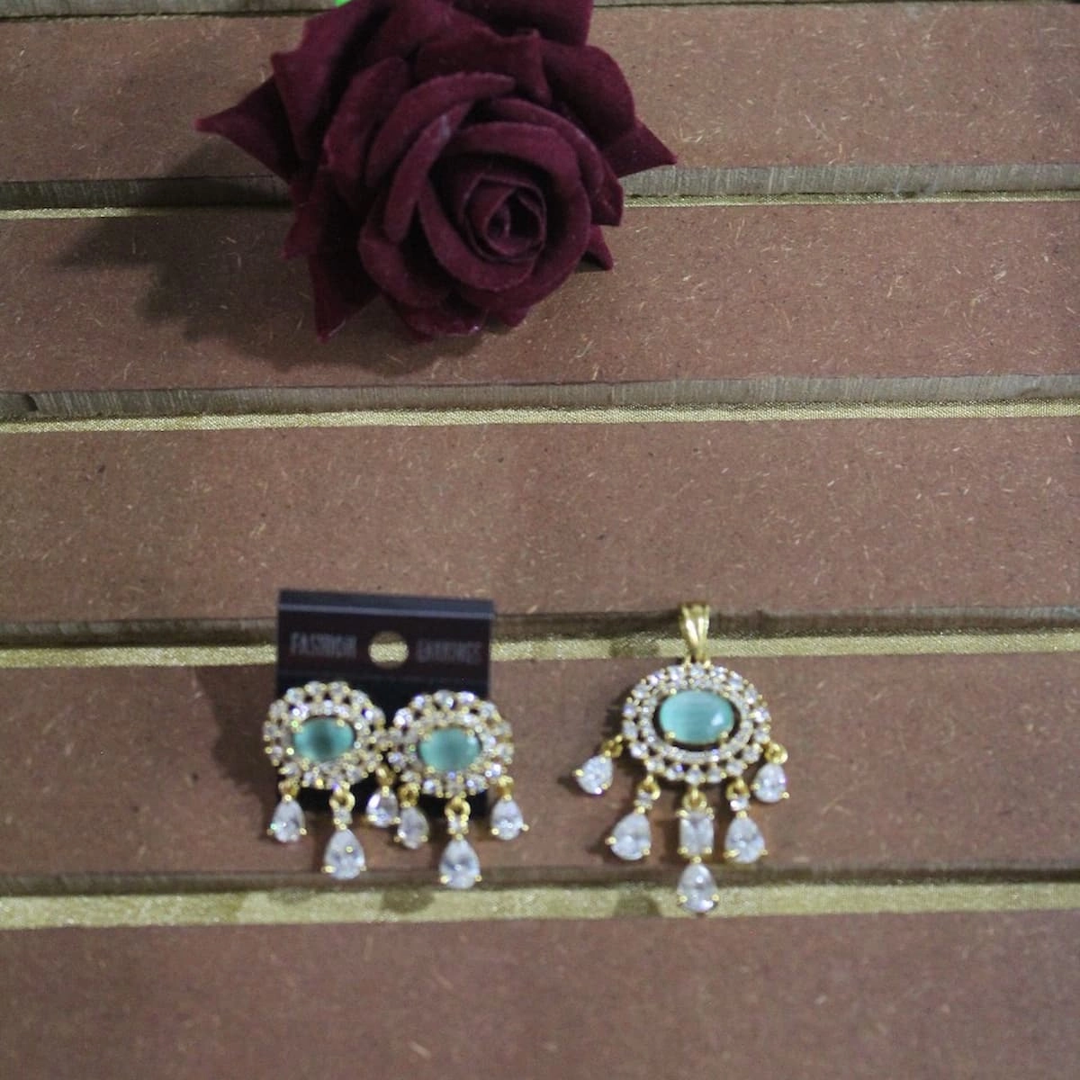 Gold-plated aqua blue oval stone earrings and matching pendant with white crystal teardrop danglers by Tisuma Jewels
