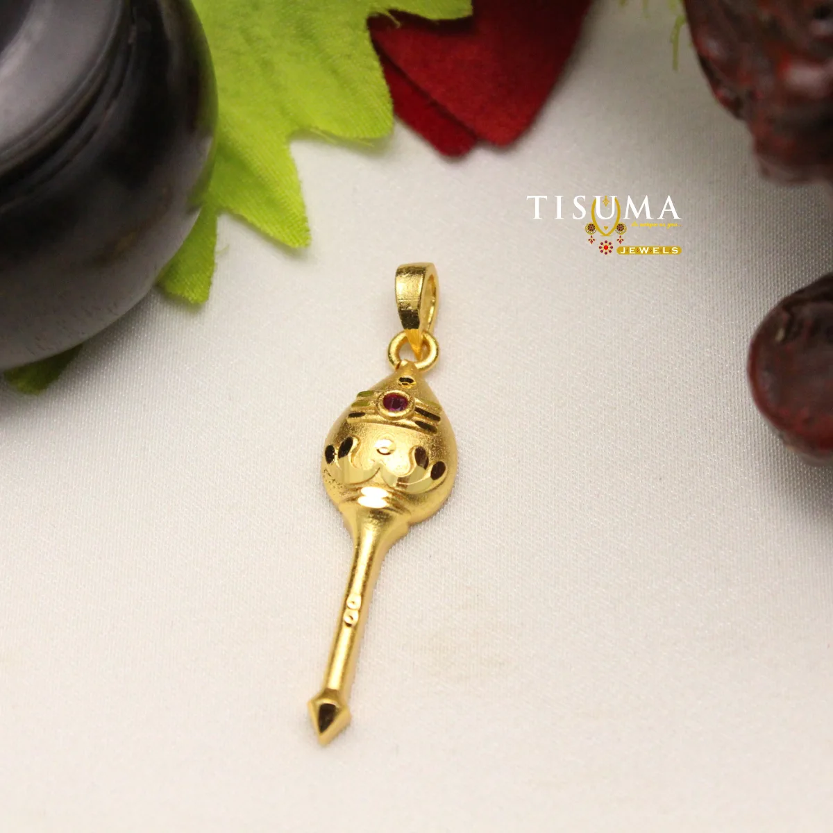 TISUMA JEWELS gold-tone traditional pendant with red stone and black detailing.