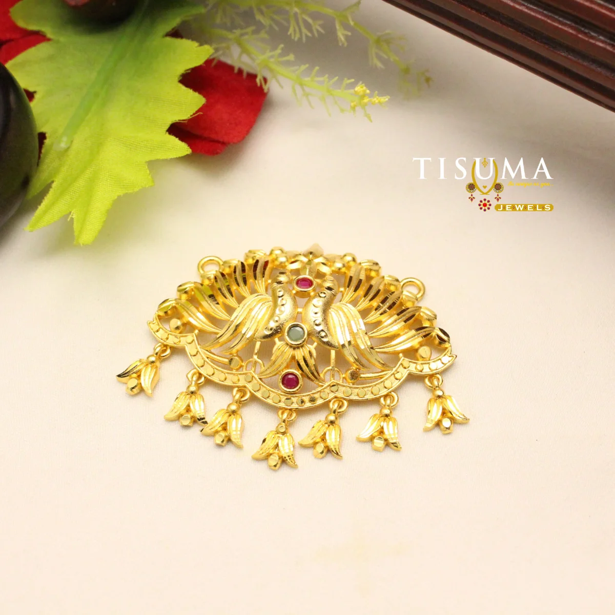 TISUMA JEWELS traditional gold-tone pendant with red and green stones and decorative hanging details.