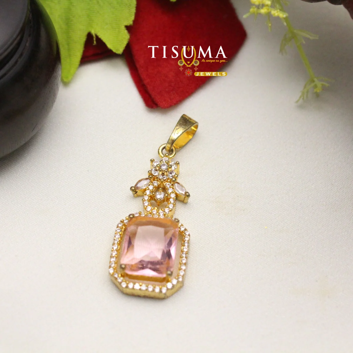 Gold-tone designer pendant with a large pink rectangular stone and clear stone accents