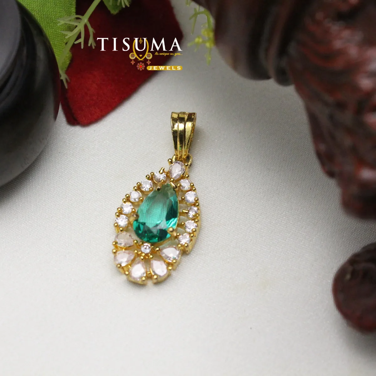 Gold-tone pendant with emerald green teardrop stone and white and pink accent stones