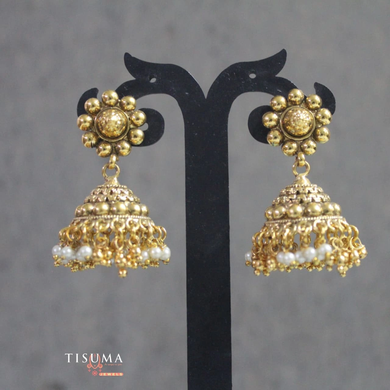 Gold tone traditional jhumka earrings with floral studs, ornate domes and white pearl-style accents